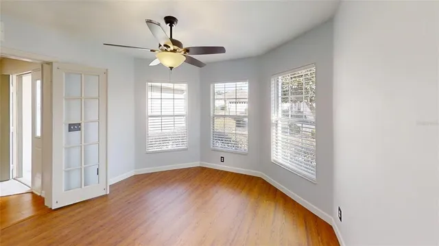 a view of an empty room with wooden floor and a window