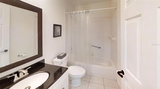 a bathroom with a granite countertop toilet a sink and a mirror