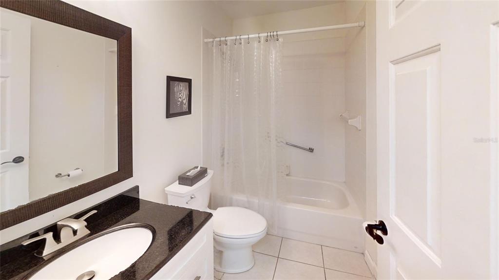 9761 Southwest 90th Street Ocala, FL 34481 - Photo 23 of 27 a bathroom with a granite countertop toilet a sink and a mirror