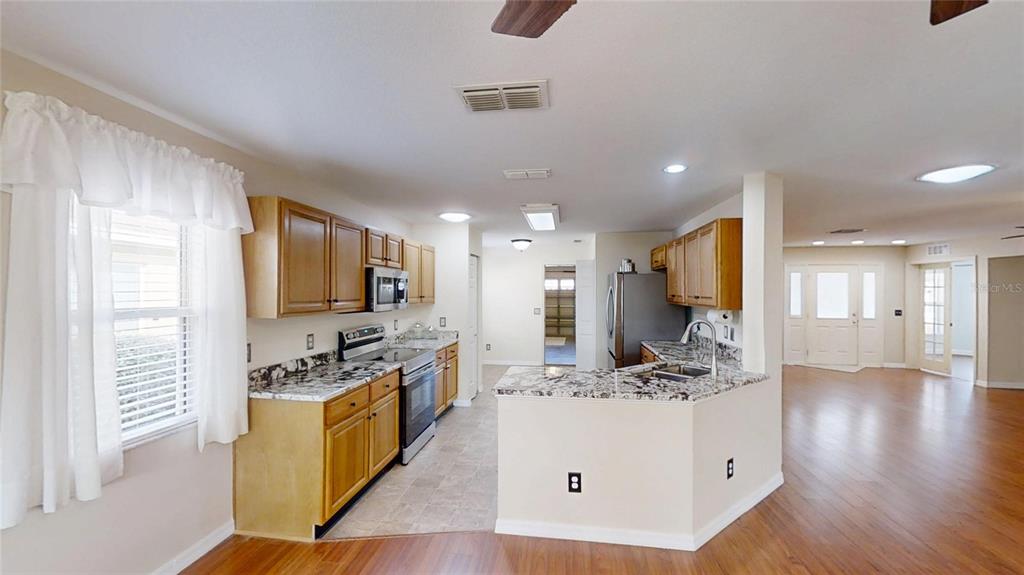 9761 Southwest 90th Street Ocala, FL 34481 - Photo 9 of 27 a kitchen with stainless steel appliances kitchen island granite countertop a stove a sink and a refrigerator