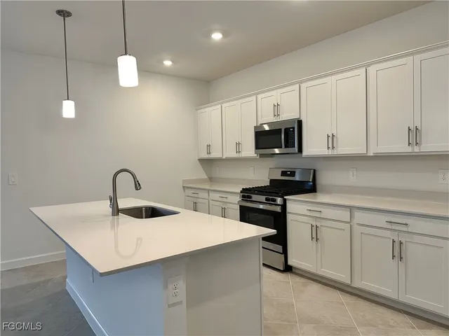 a kitchen with stainless steel appliances granite countertop a sink a microwave a stove and white cabinets