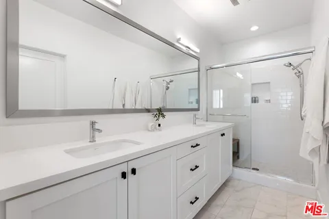 a bathroom with a double vanity sink mirror and shower