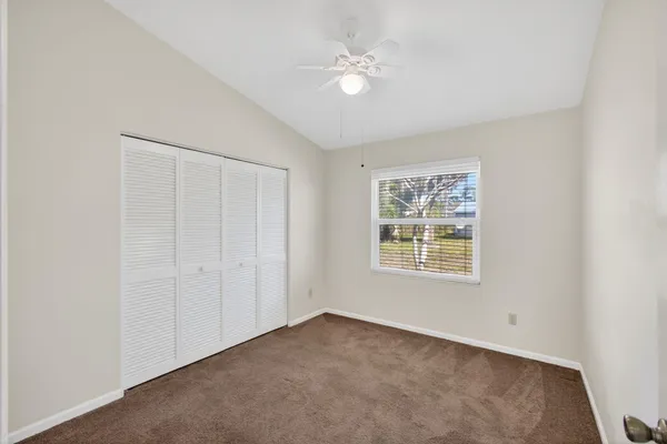 an empty room with windows and ceiling fan