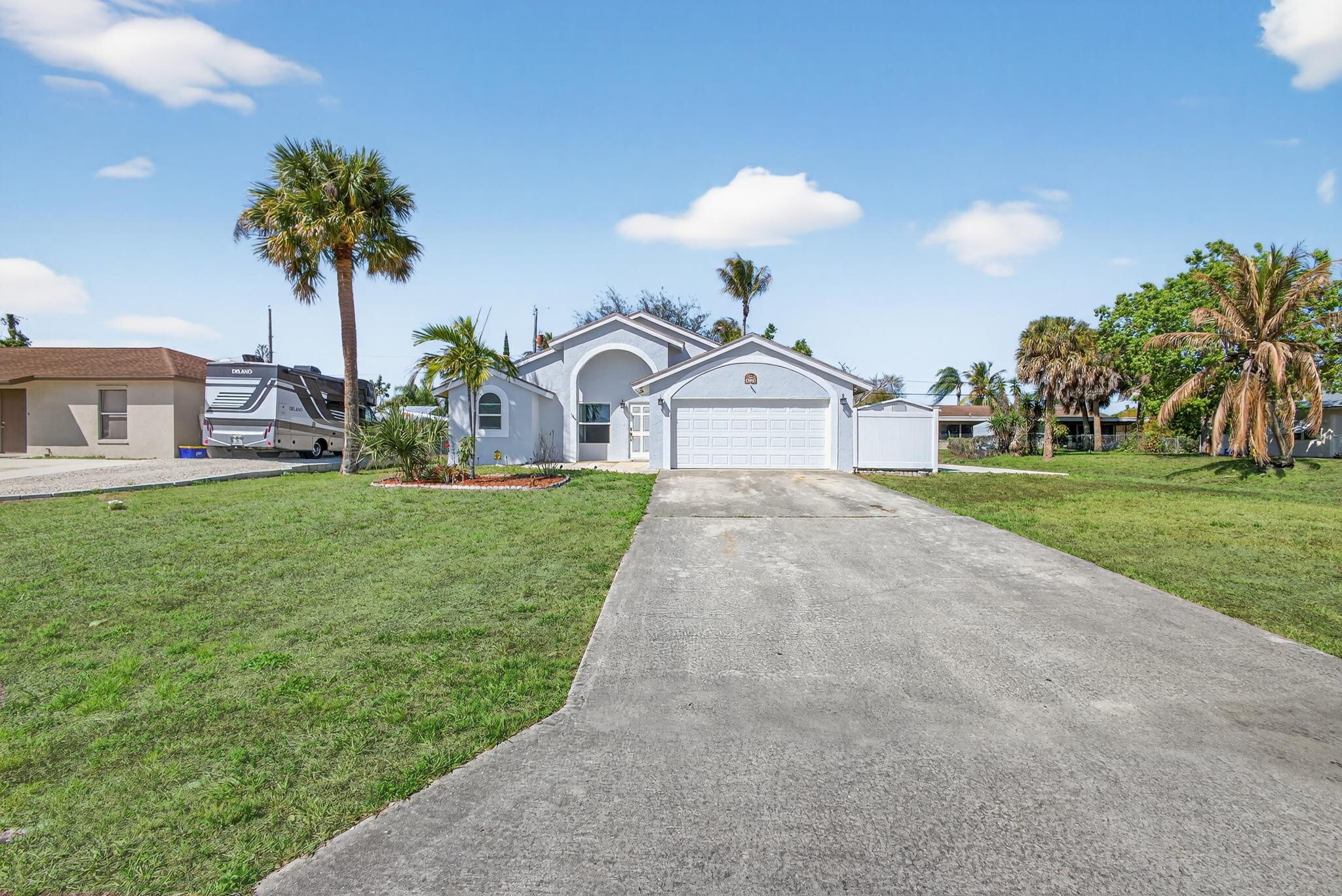 6223 Kendrick Street Jupiter, FL 33458 - Photo 31 of 45 a view of a house with a big yard potted plants and palm trees