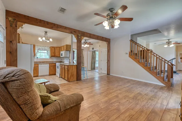 a living room with furniture with kitchen view and a chandelier