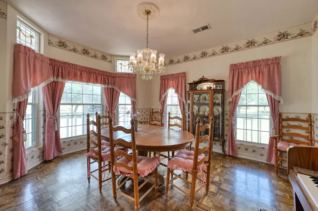 a dining room with furniture a chandelier and wooden floor
