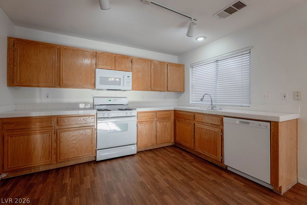8379 Rockefeller Street Las Vegas, NV 89123 - Photo 12 of 36 Rich wood flooring runs throughout this functional kitchen space complete with extensive oak cabinetry.
