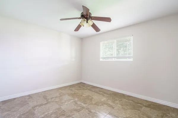 an empty room with a window and a fan