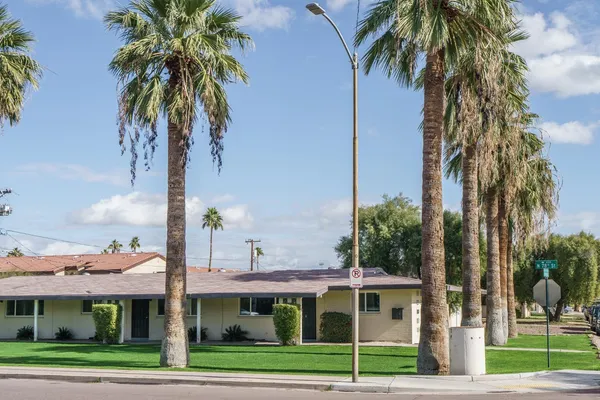 a front view of a house with a garden and trees