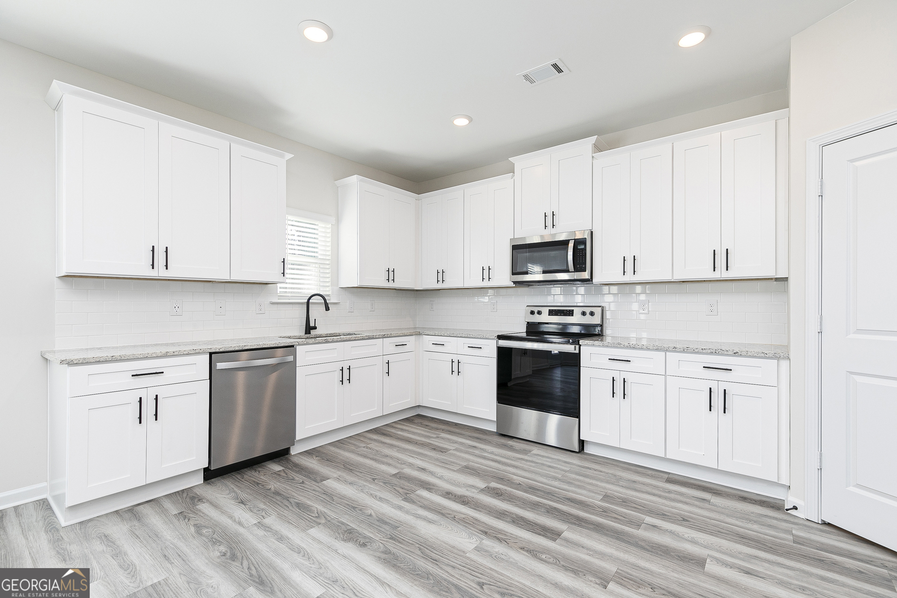 161 Sunfish Circle Hoschton, GA 30548 - Photo 5 of 13 a kitchen with granite countertop white cabinets and appliances