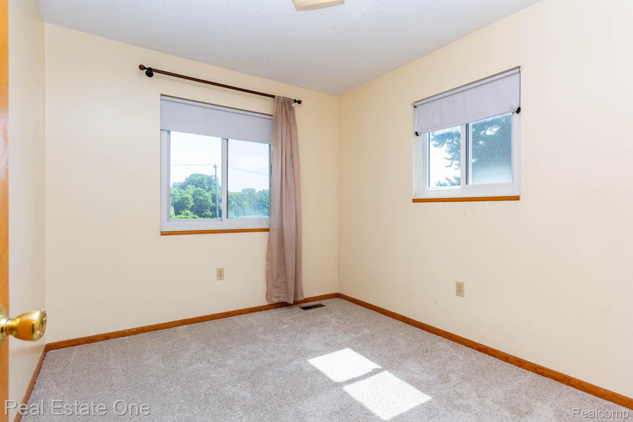 13912 Clinton River Road Sterling Heights, MI 48313 - Photo 17 of 43 Carpeted room with two windows, painted walls, and wood-finish trim