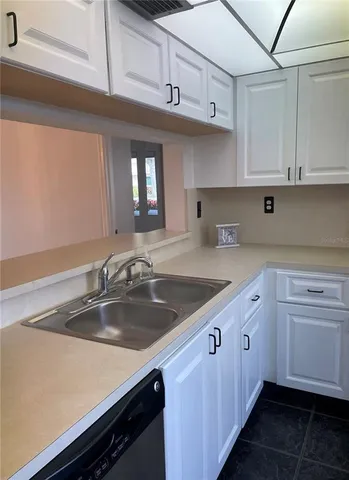 a kitchen with stainless steel appliances a sink dishwasher a stove and white cabinets