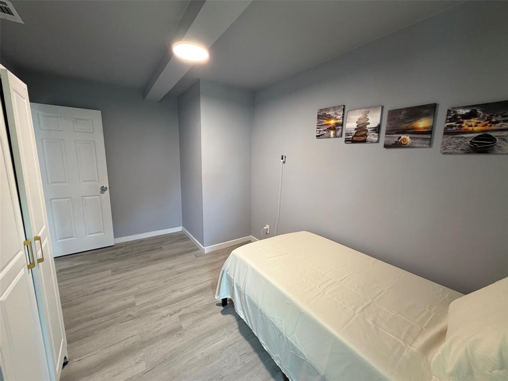 714 Southwest Dallas Street Grand Prairie, TX 75051 - Photo 7 of 27 Spacious room with light gray walls and wood-finish flooring