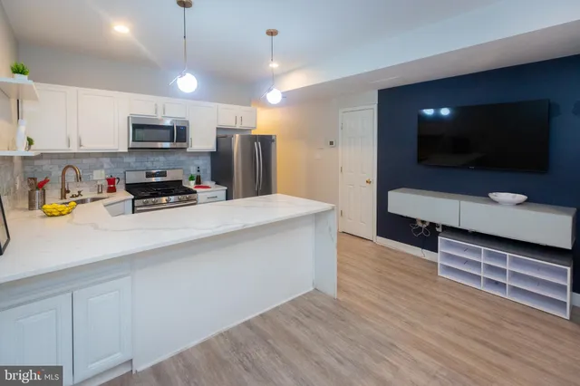 a kitchen with stainless steel appliances a refrigerator a stove a microwave oven a sink with wooden floor and cabinets