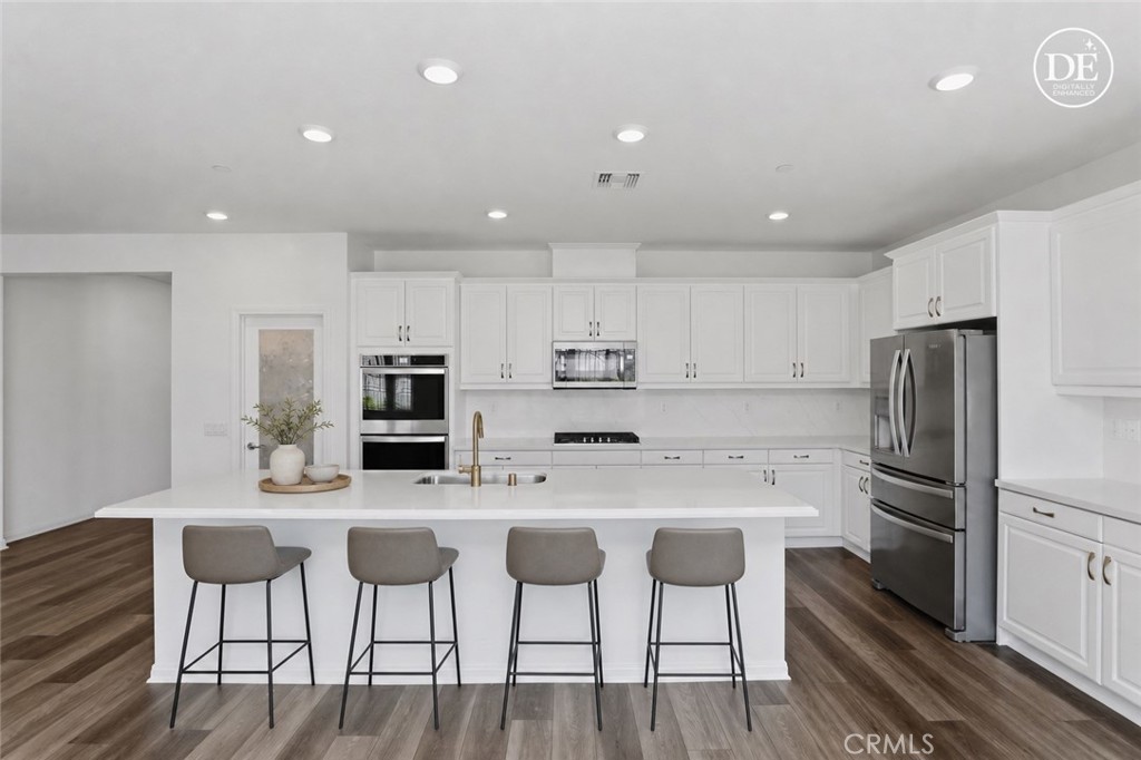 21159 Blue Jeans Court Riverside, CA 92507 - Photo 31 of 63 a kitchen with stainless steel appliances kitchen island granite countertop a dining table chairs refrigerator and sink