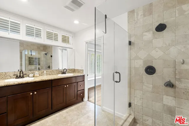 a bathroom with a double vanity sink mirror and shower