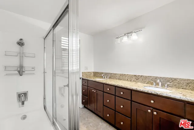 a bathroom with a granite countertop sink a mirror and shower