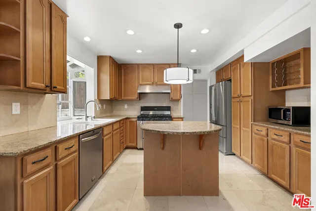 a large kitchen with stainless steel appliances granite countertop a stove a sink dishwasher a refrigerator and cabinets with wooden floor