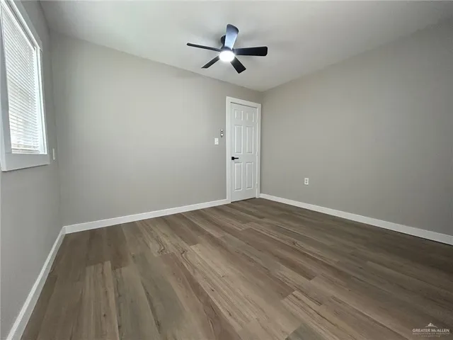 an empty room with wooden floor and ceiling fan