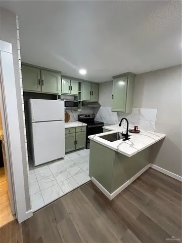 a kitchen with a sink stainless steel appliances a refrigerator and a stove top oven