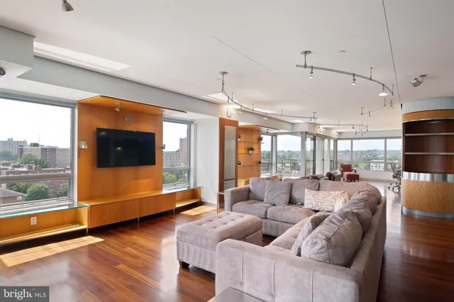 a living room with couches and dining table with wooden floor
