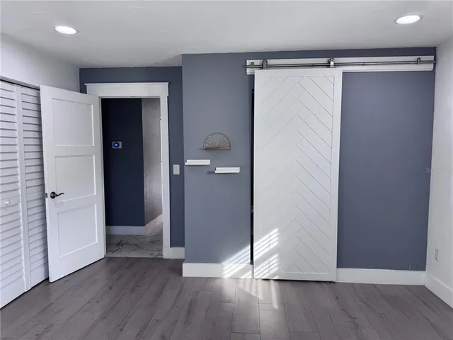 an empty room with wooden floor & closet area