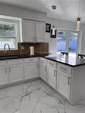 a kitchen with white cabinets and sink