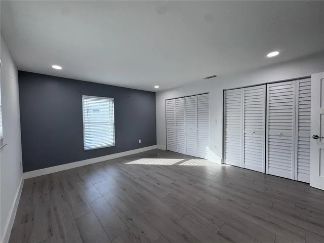 a view of an empty room with wooden floor and closet