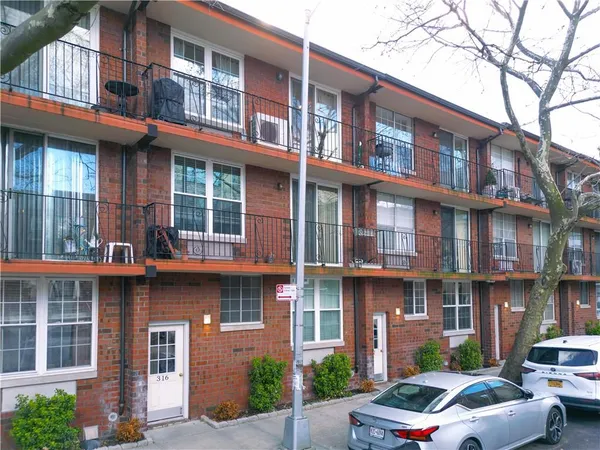 a front view of a building with a garden and parking space