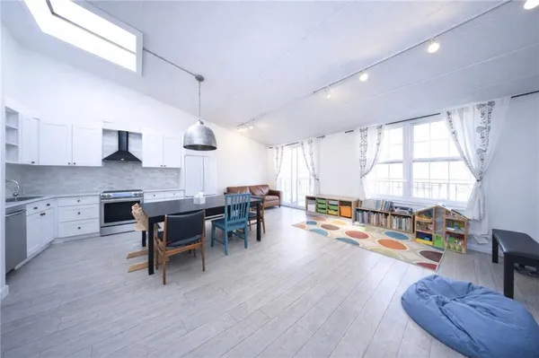 a kitchen with stainless steel appliances granite countertop a stove a sink a dining table and chairs with wooden floor