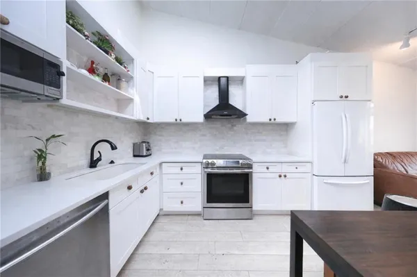 a kitchen with stainless steel appliances granite countertop a sink a stove and a refrigerator