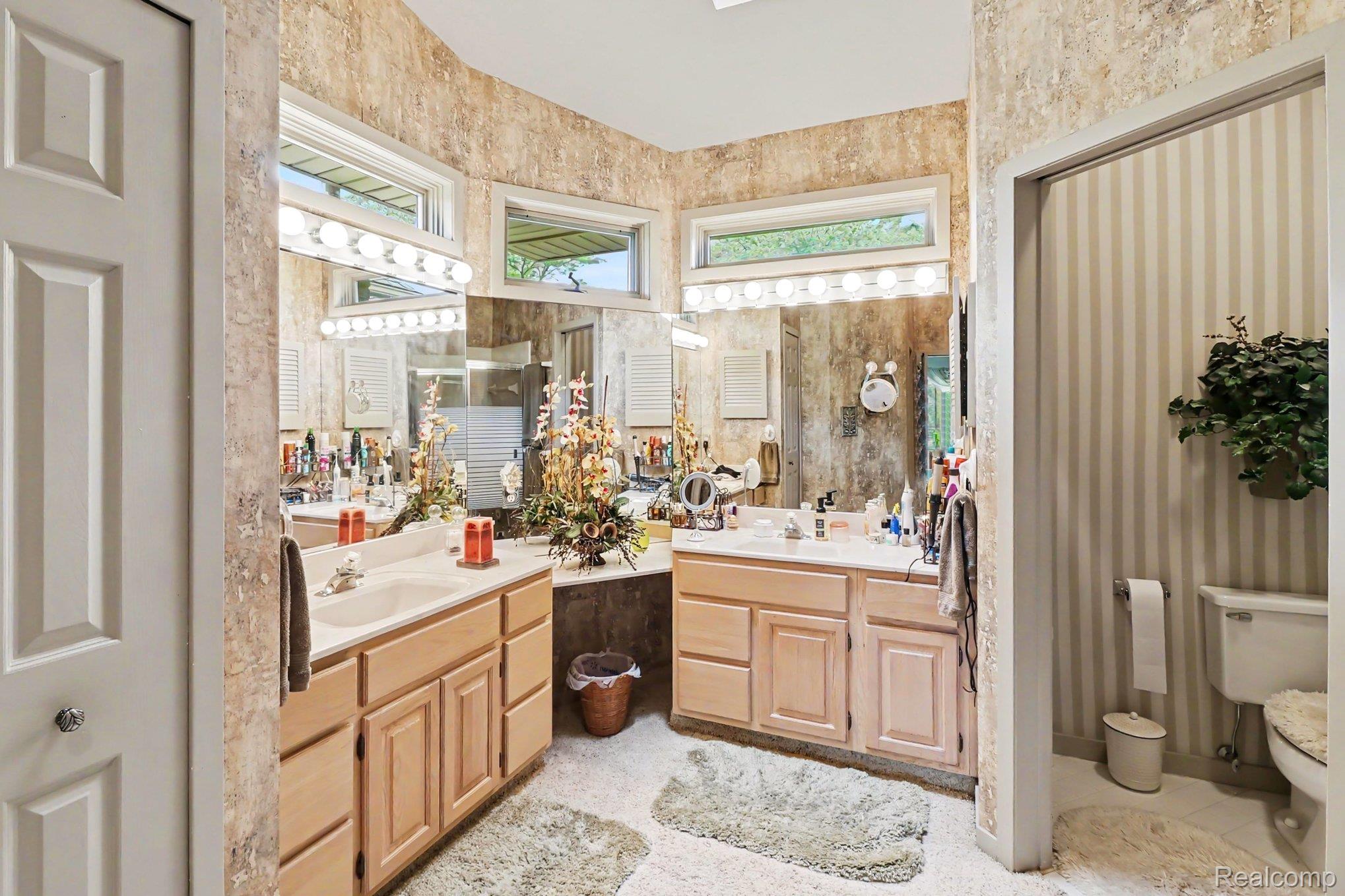 18501 Taylor Lake Road Holly, MI 48442 - Photo 19 of 35 Double vanity featuring wood-finish cabinetry, integrated sinks, and overhead strip lighting