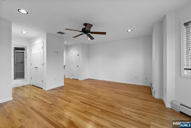 a view of empty room with wooden floor and fan
