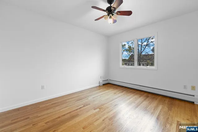 a view of an empty room with window and wooden floor