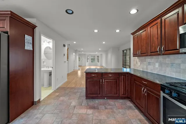 a large kitchen with stainless steel appliances granite countertop a sink and cabinets