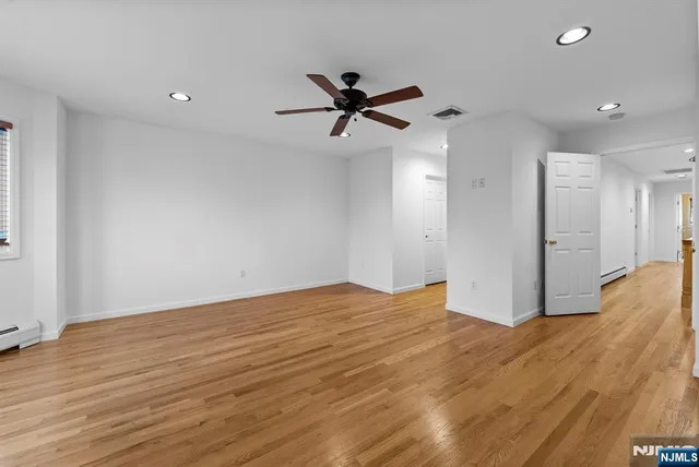 a view of empty room with wooden floor and fan