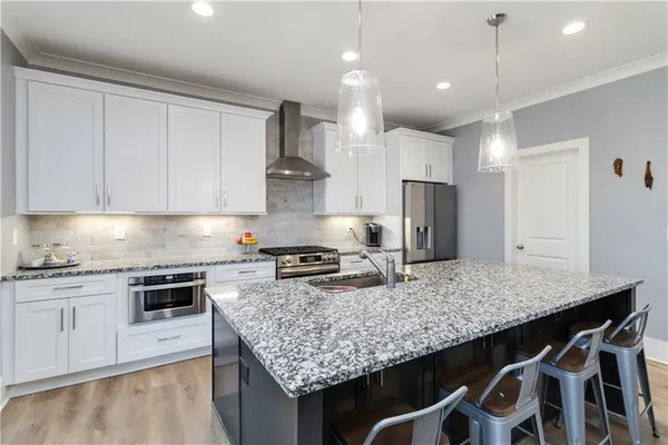 a kitchen with granite countertop kitchen island stainless steel appliances a stove a sink and cabinets