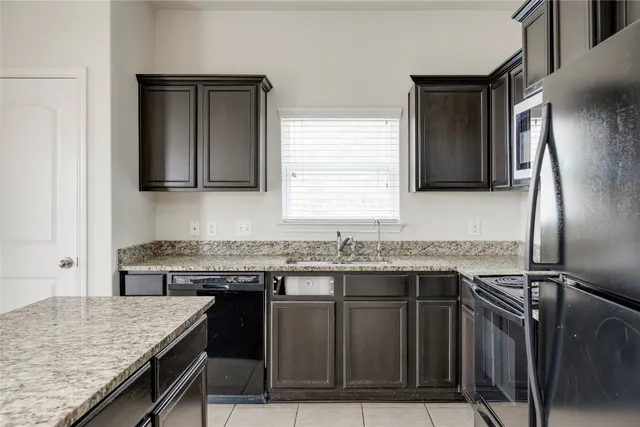 a kitchen with granite countertop a sink stove and refrigerator