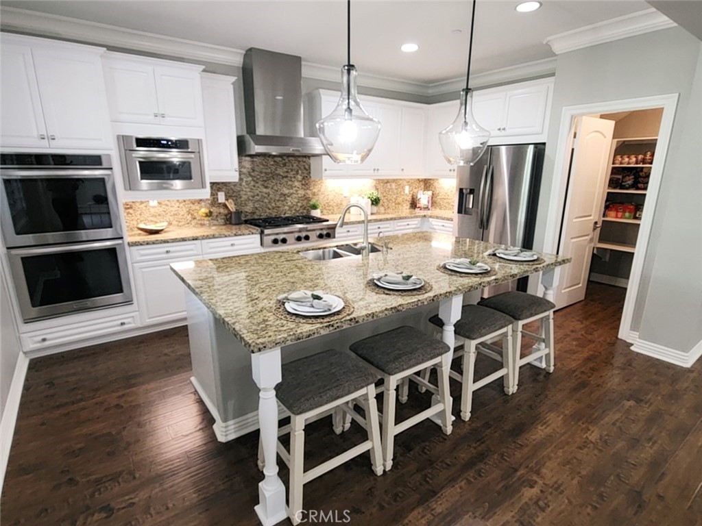 23 Vivido Street Rancho Mission Viejo, CA 92694 - Photo 11 of 44 a kitchen with stainless steel appliances granite countertop a stove refrigerator and a wooden floor