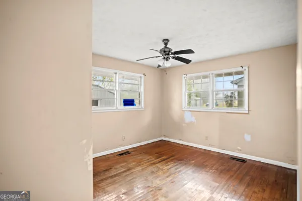a view of a big room with wooden floor and windows