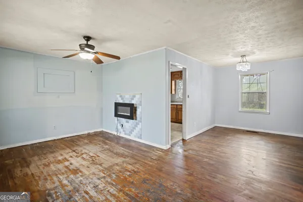 a view of empty room with wooden floor and fan