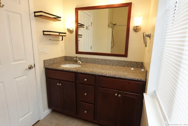 a bathroom with a granite countertop sink and a mirror