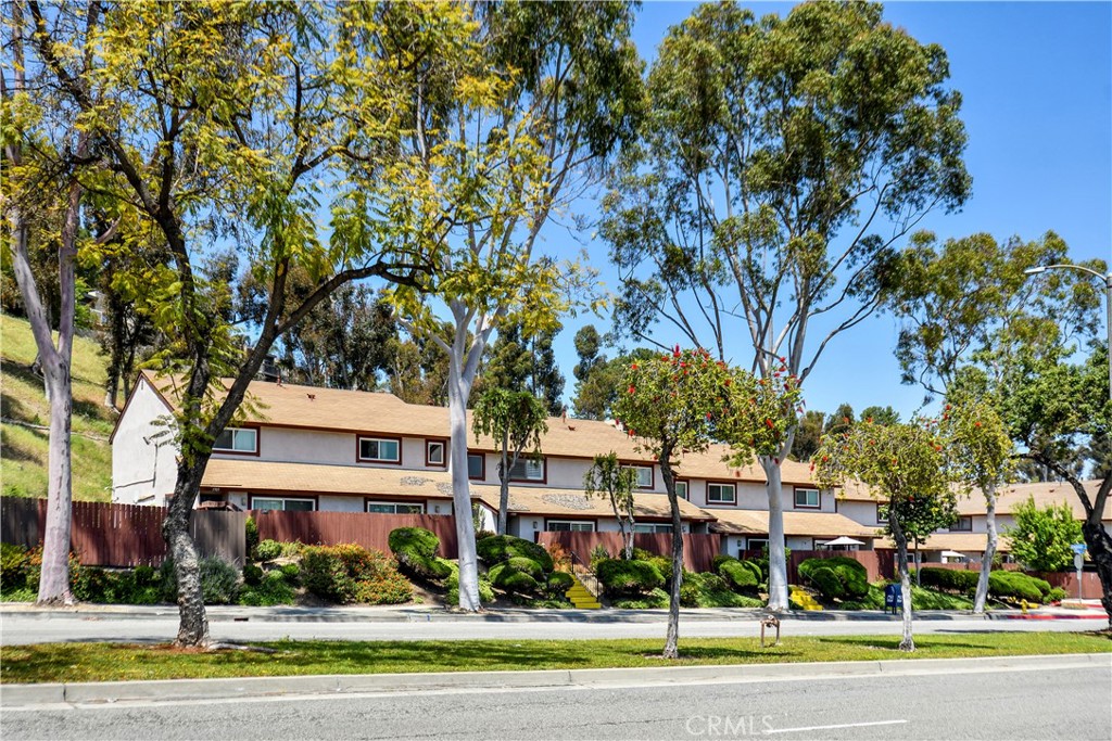 a view of a white house with a swimming pool and lawn chairs under an umbrella