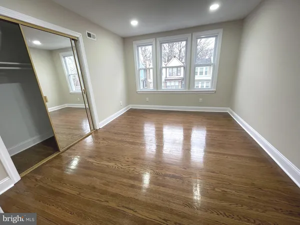 an empty room with wooden floor and mirror