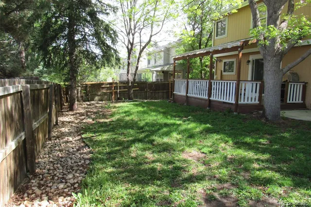 a view of a backyard with large trees and wooden fence