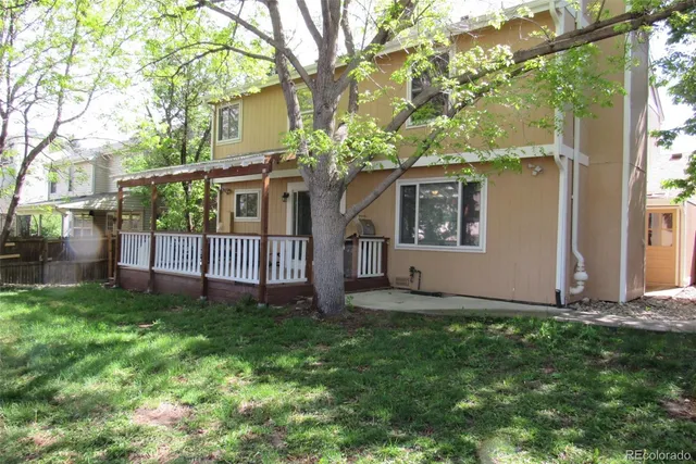 a view of a house with a yard and a large tree