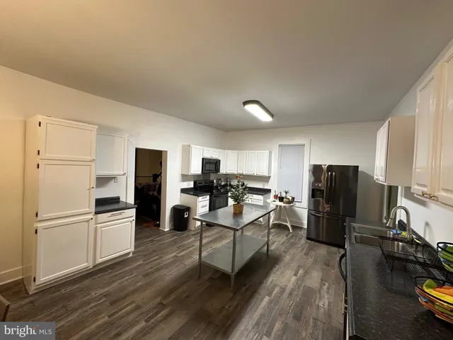 a kitchen with a refrigerator a stove top oven a sink dishwasher and white cabinets with wooden floor