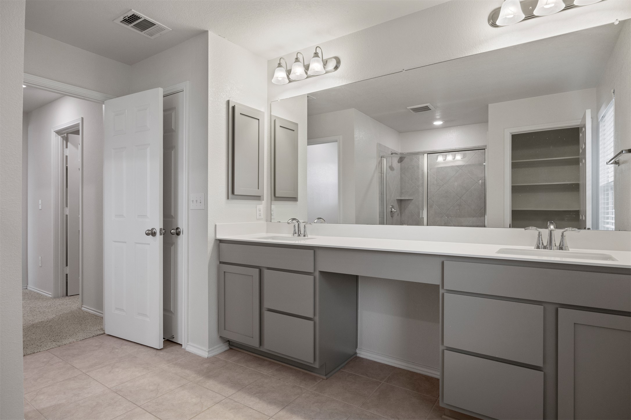 7009 Nutria Run Austin, TX 78744 - Photo 11 of 15 A well-appointed primary bathroom features a dual vanity with ample counter space and a spacious shower.