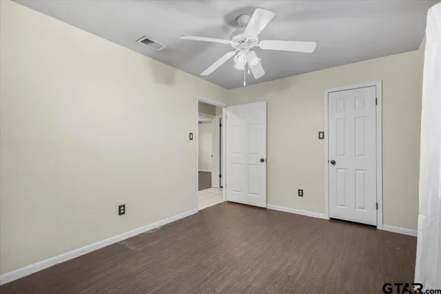 an empty room with wooden floor and ceiling fan