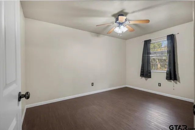 an empty room with wooden floor chandelier fan and windows